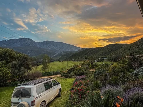 Parked vehicle facing golden sunrise at OudeMuragie